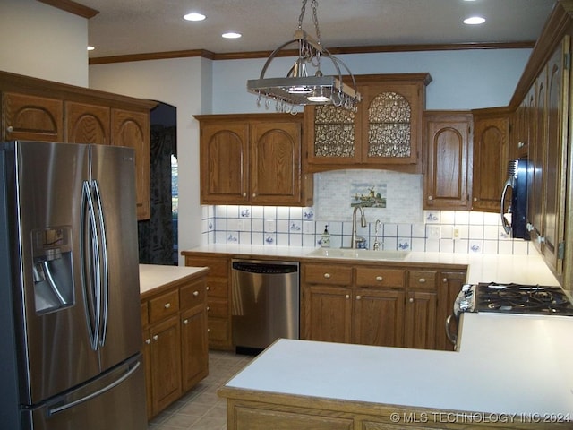 kitchen with sink, stainless steel appliances, pendant lighting, decorative backsplash, and ornamental molding