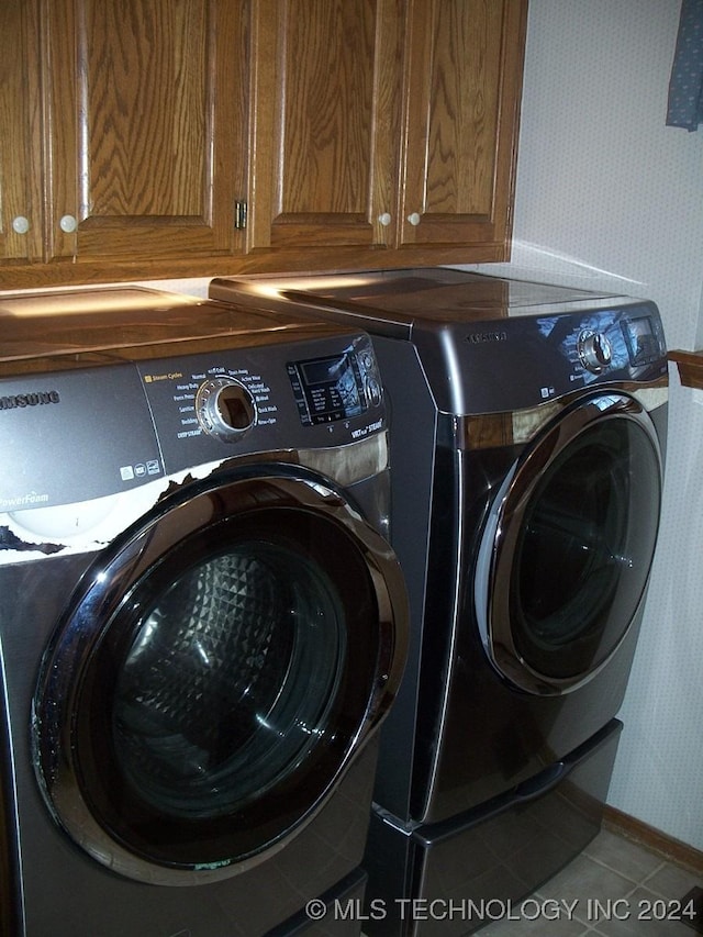 laundry area featuring cabinets, tile patterned floors, and washing machine and clothes dryer