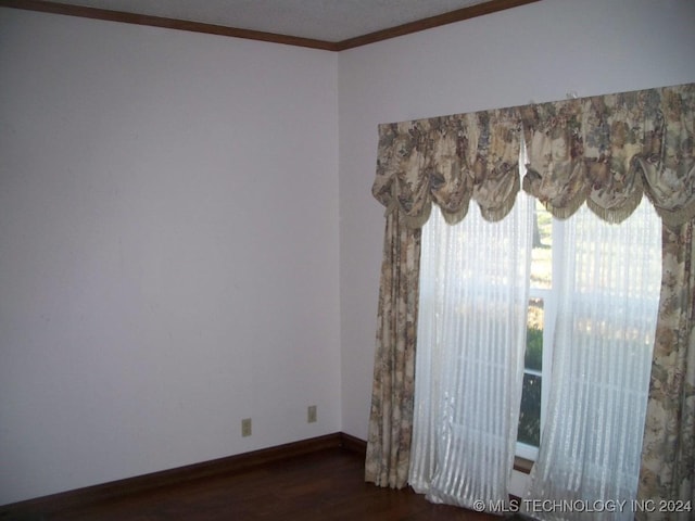 empty room featuring dark hardwood / wood-style floors and crown molding