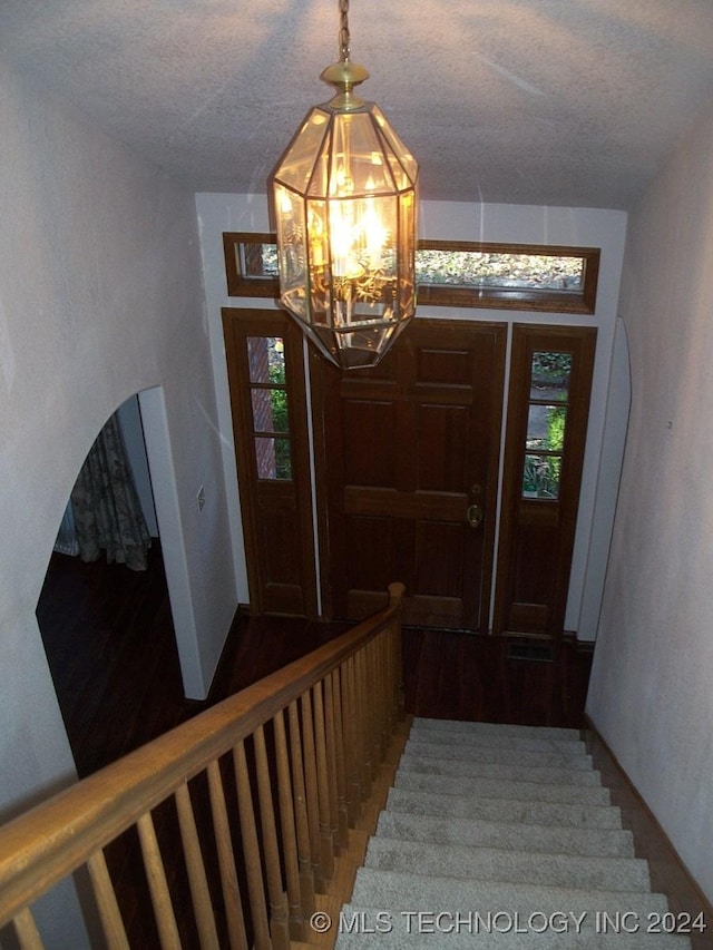 entrance foyer featuring an inviting chandelier, a healthy amount of sunlight, and hardwood / wood-style flooring