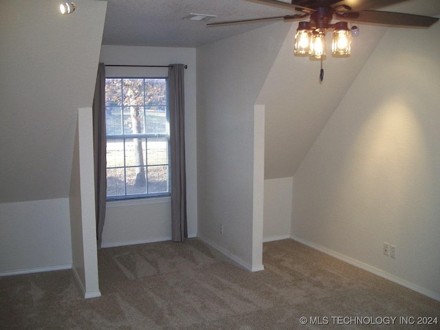 bonus room featuring dark colored carpet, a textured ceiling, vaulted ceiling, and ceiling fan