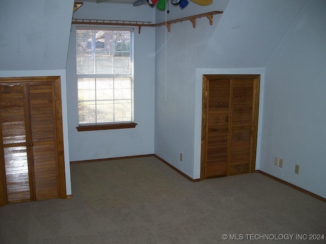 unfurnished bedroom with carpet, ceiling fan, a closet, and vaulted ceiling