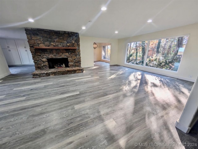 unfurnished living room featuring wood-type flooring and a stone fireplace