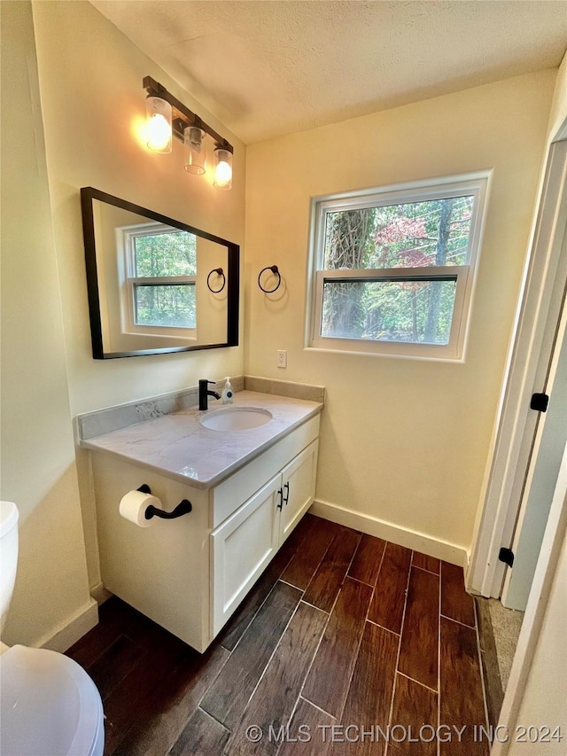 bathroom featuring hardwood / wood-style flooring, plenty of natural light, toilet, and vanity