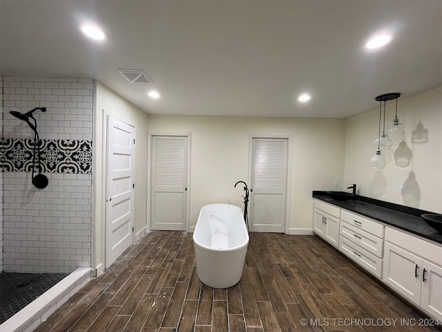 bathroom with plus walk in shower, hardwood / wood-style floors, and vanity