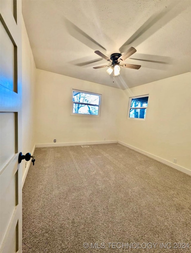 carpeted spare room featuring ceiling fan and a textured ceiling