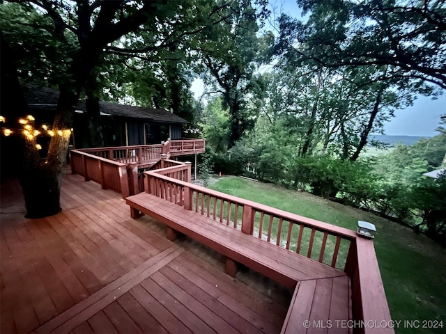 deck at dusk featuring a lawn