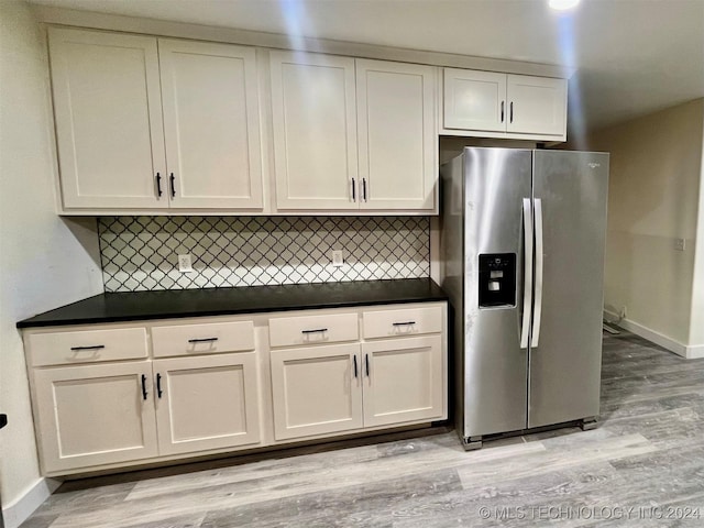 kitchen featuring white cabinets, decorative backsplash, light hardwood / wood-style floors, and stainless steel refrigerator with ice dispenser