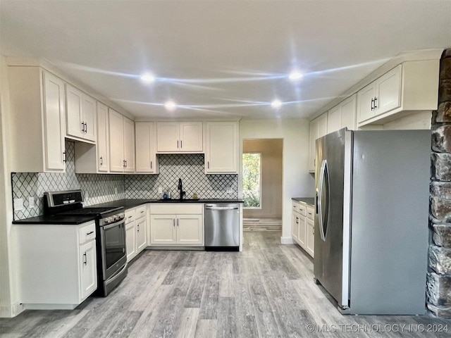 kitchen featuring sink, stainless steel appliances, tasteful backsplash, white cabinets, and light wood-type flooring