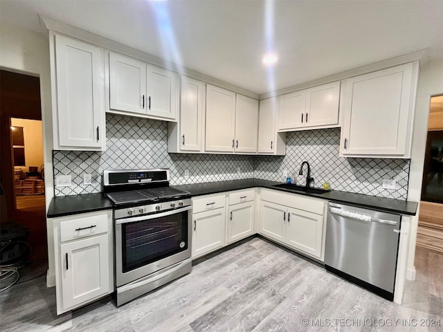 kitchen featuring sink, stainless steel appliances, tasteful backsplash, white cabinets, and light wood-type flooring