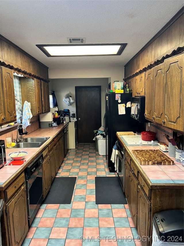 10722 E First St, Claremore, OK 74019 - kitchen with tile counters, dishwasher, a sink, black microwave, and oven