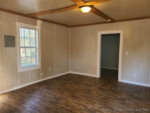 empty room with beam ceiling, electric panel, dark wood-type flooring, and wood walls