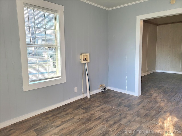 unfurnished room with a healthy amount of sunlight, ornamental molding, dark wood-type flooring, and wooden walls