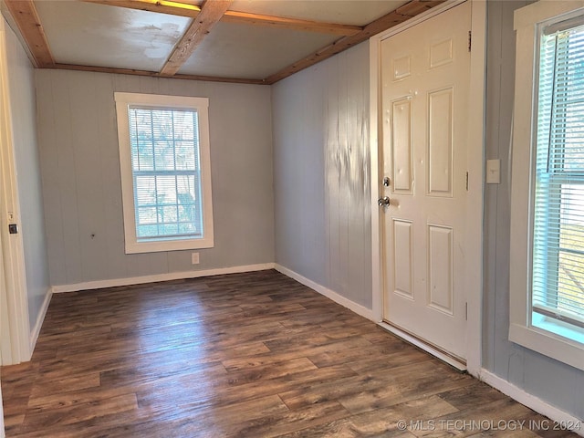 spare room featuring beam ceiling, wooden walls, and dark wood-type flooring