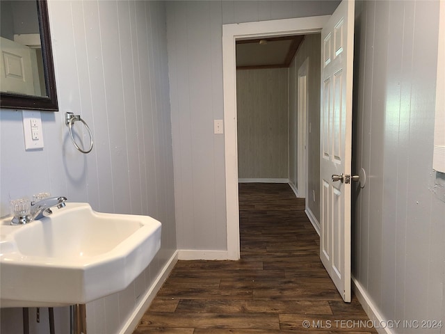 bathroom featuring hardwood / wood-style floors, wood walls, and sink