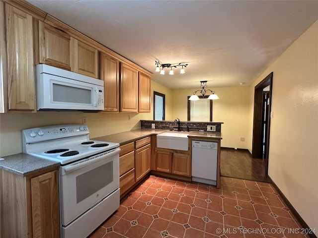 kitchen with pendant lighting, white appliances, sink, kitchen peninsula, and a chandelier