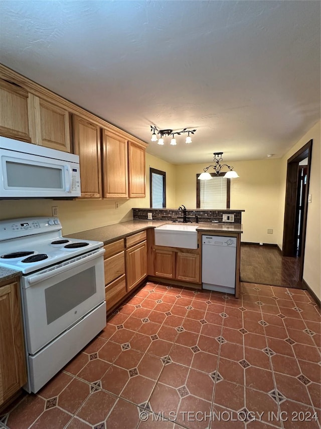 kitchen with kitchen peninsula, white appliances, and sink