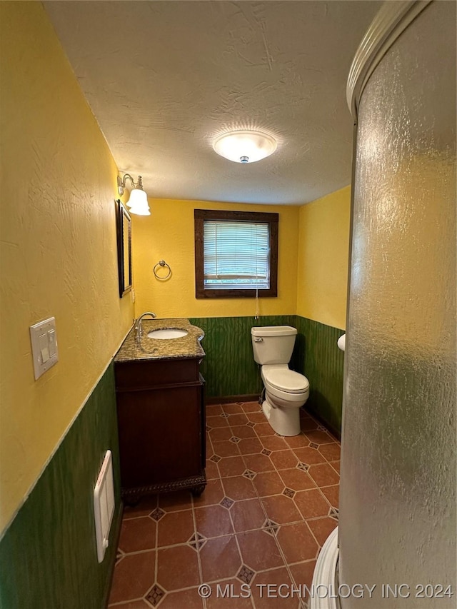 bathroom featuring tile patterned floors, vanity, toilet, and a textured ceiling