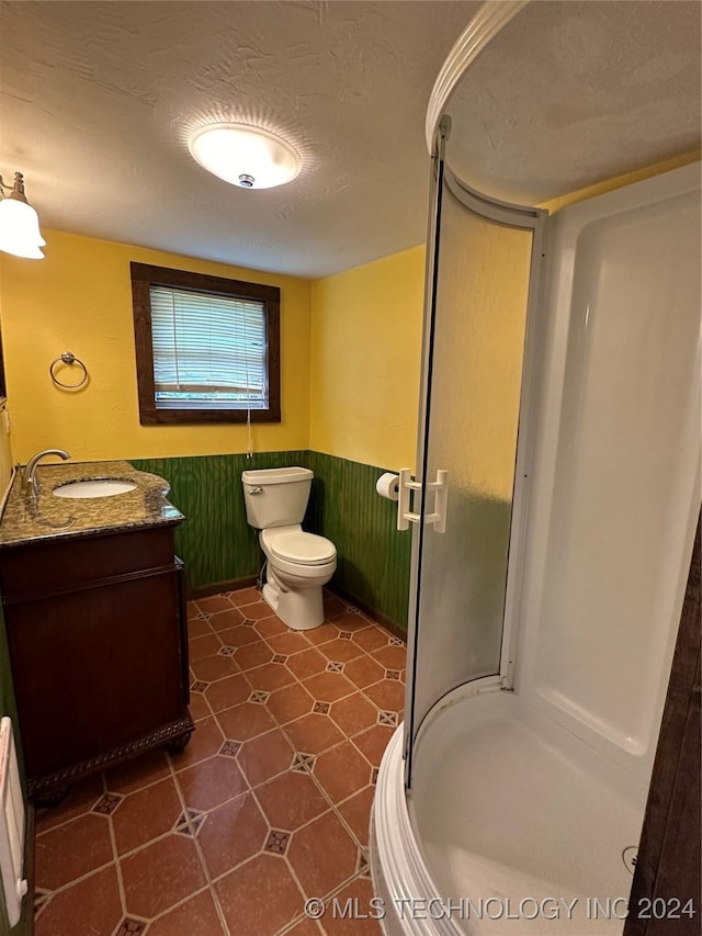 bathroom featuring tile patterned floors, walk in shower, a textured ceiling, vanity, and toilet