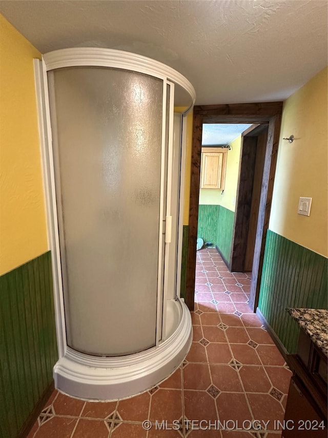 bathroom featuring tile patterned flooring, a textured ceiling, vanity, and a shower with door