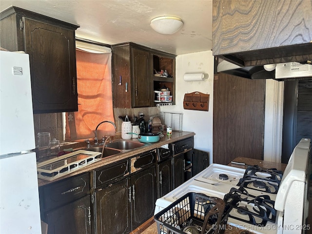 kitchen featuring premium range hood, white appliances, a sink, dark brown cabinets, and open shelves