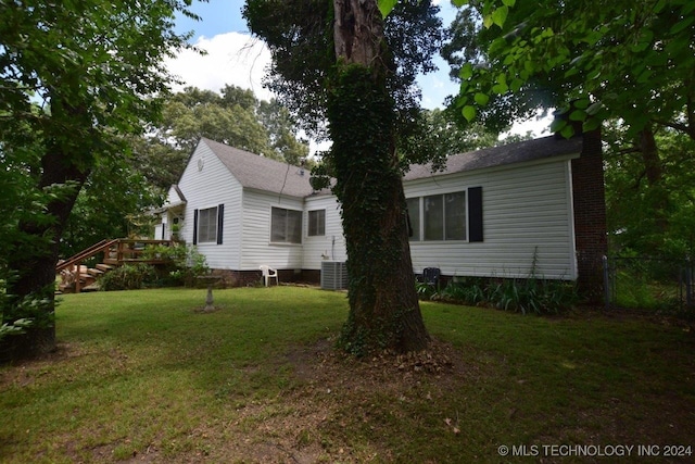 view of side of home with a lawn, central AC unit, and a deck