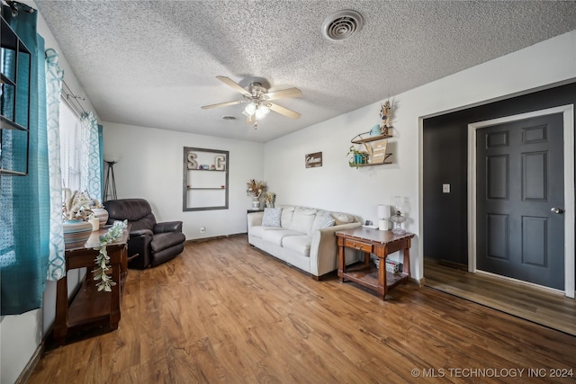 living room with hardwood / wood-style floors, ceiling fan, and a textured ceiling