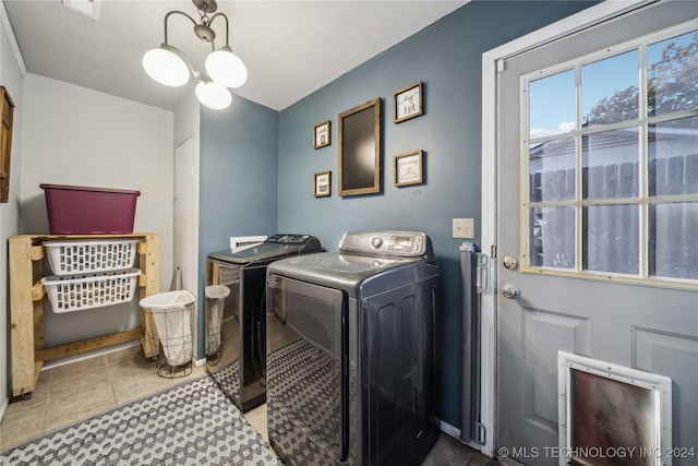 laundry room with tile patterned floors, washing machine and dryer, and a notable chandelier