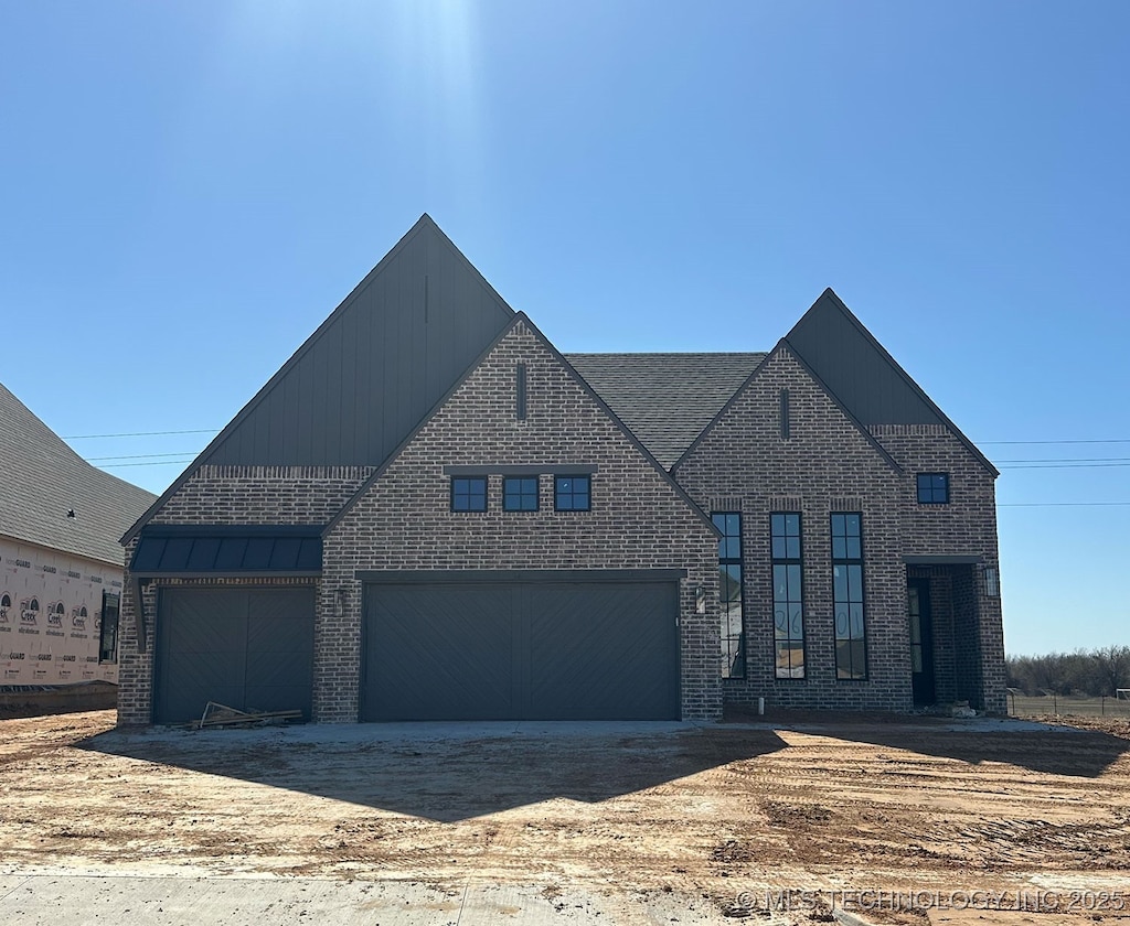 view of front facade featuring brick siding, dirt driveway, a standing seam roof, metal roof, and a garage