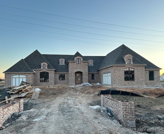 french country style house with brick siding and roof with shingles