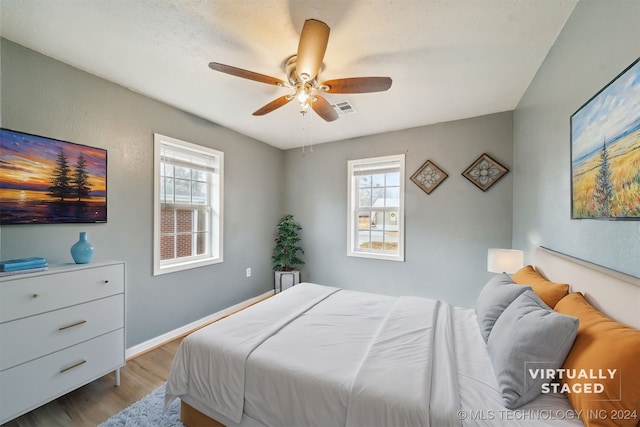 bedroom featuring ceiling fan, light hardwood / wood-style floors, and multiple windows