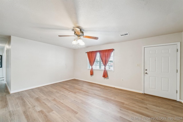 empty room featuring ceiling fan, light wood-type flooring, and a textured ceiling