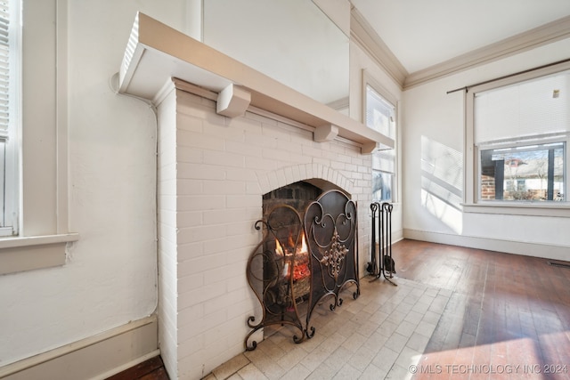 interior details featuring crown molding, hardwood / wood-style floors, and a brick fireplace