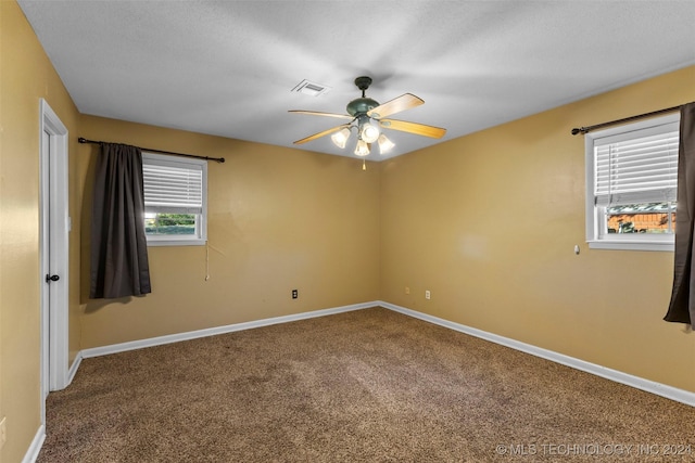 carpeted empty room with ceiling fan, a healthy amount of sunlight, and a textured ceiling