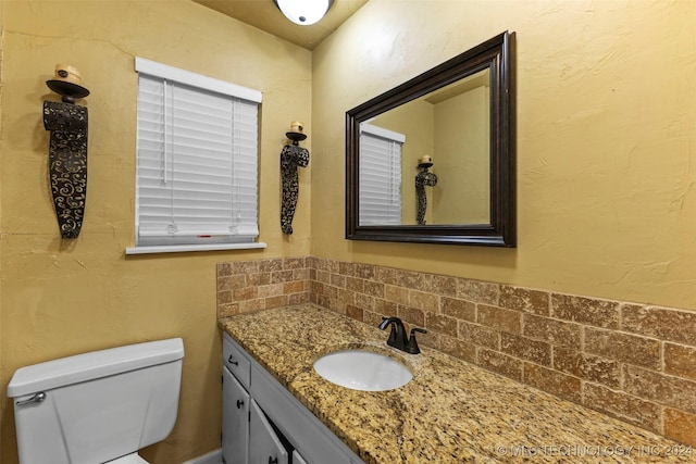 bathroom with vanity, toilet, and backsplash