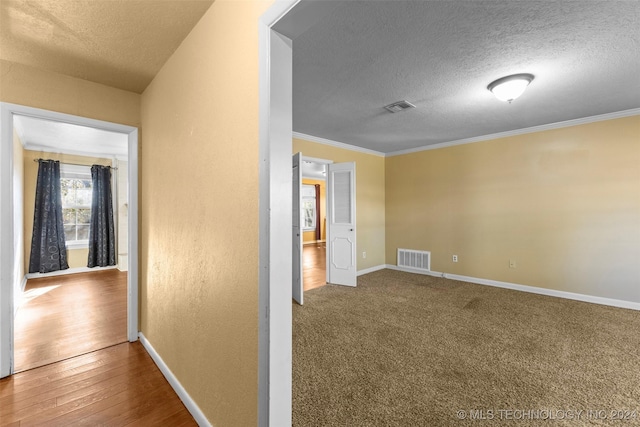 corridor with crown molding, wood-type flooring, and a textured ceiling