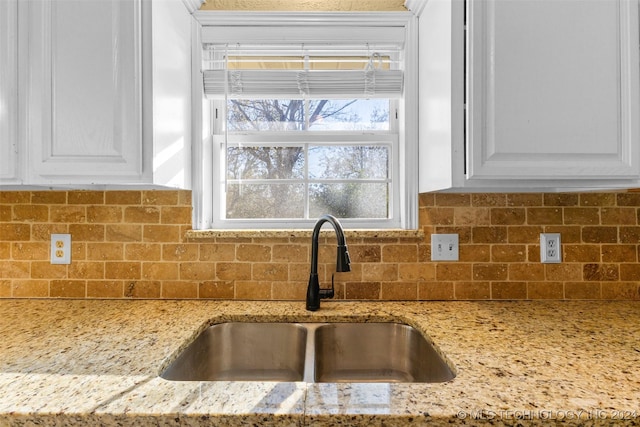 details featuring white cabinetry, light stone countertops, sink, and tasteful backsplash