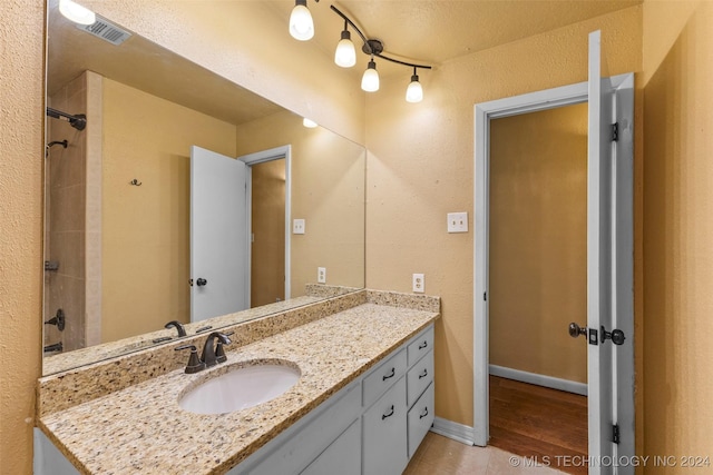 bathroom with a shower, vanity, a textured ceiling, and hardwood / wood-style flooring