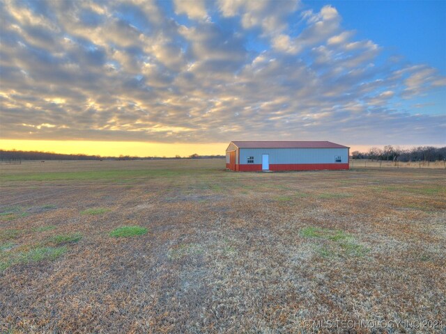 yard at dusk featuring a rural view