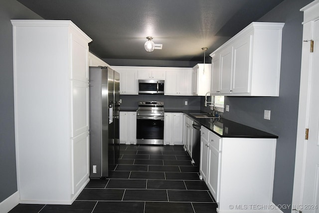 kitchen featuring a textured ceiling, stainless steel appliances, sink, decorative light fixtures, and white cabinetry