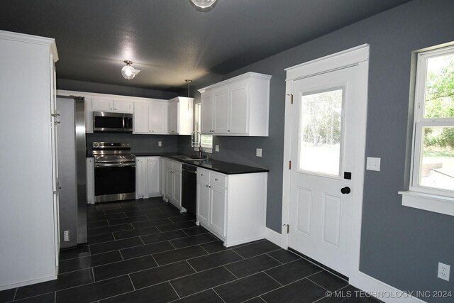 kitchen featuring white cabinets, decorative light fixtures, stainless steel appliances, and sink