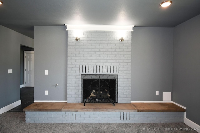 unfurnished living room featuring a fireplace, a textured ceiling, and dark carpet