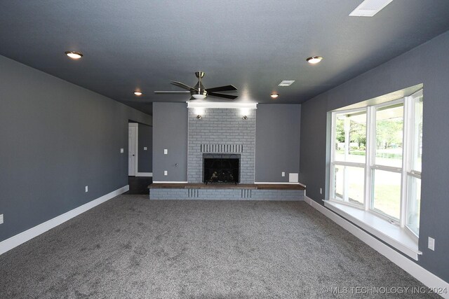 unfurnished living room with carpet flooring, ceiling fan, a fireplace, and a textured ceiling