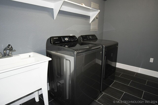 clothes washing area with dark tile patterned flooring, independent washer and dryer, and sink