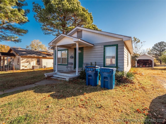 view of front of property featuring a garage, an outbuilding, and a front lawn