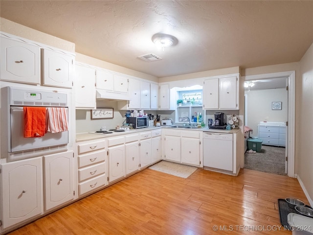 kitchen featuring sink, white cabinets, light hardwood / wood-style floors, and white appliances