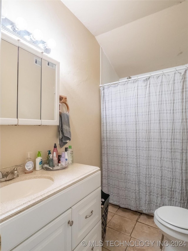 bathroom featuring tile patterned flooring, vanity, toilet, and lofted ceiling