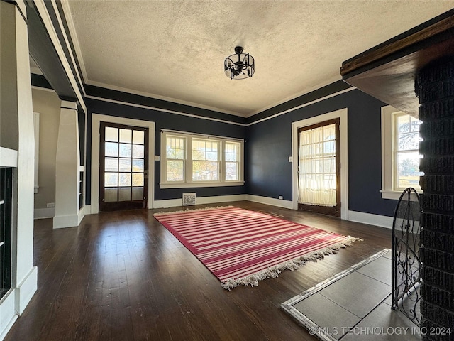 entryway featuring a chandelier, dark wood-type flooring, a healthy amount of sunlight, and a textured ceiling