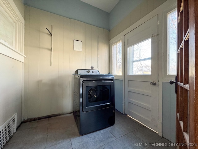 clothes washing area with washer / clothes dryer and wood walls