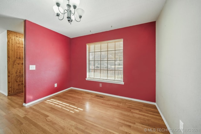 empty room featuring an inviting chandelier and hardwood / wood-style flooring